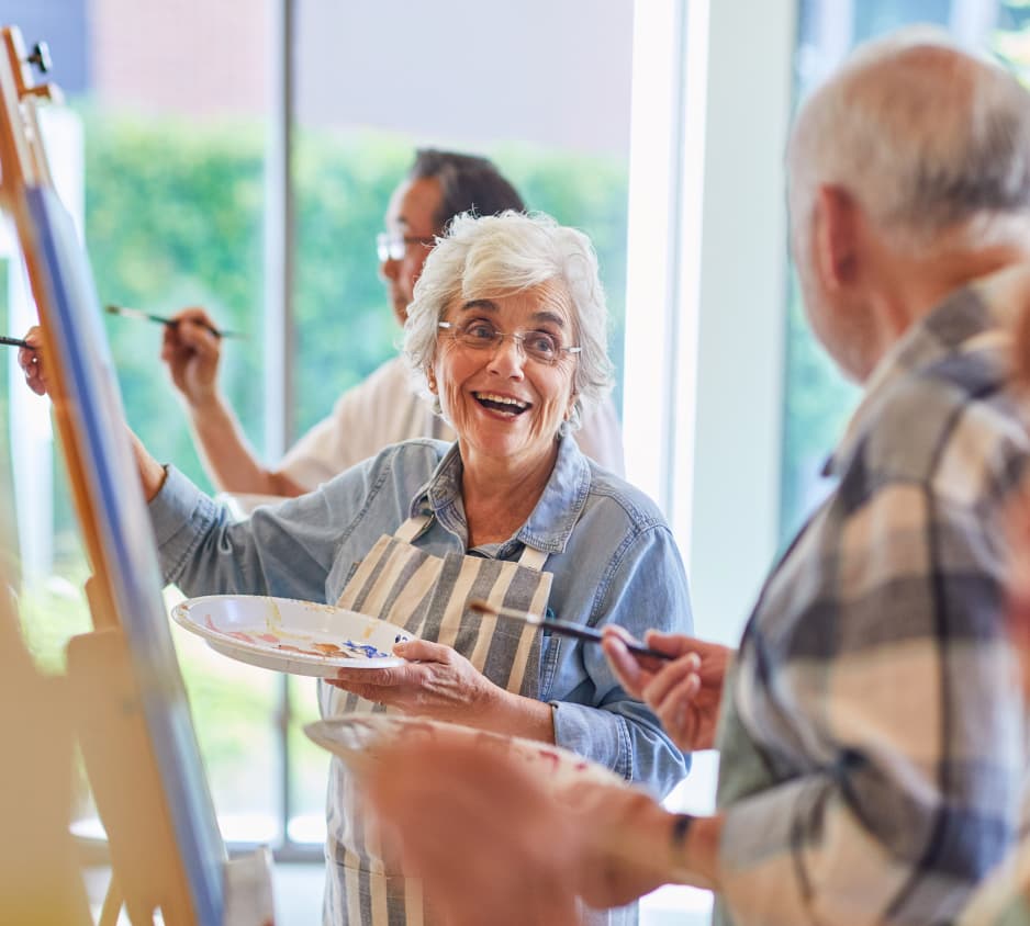 Two people smile at each other while painting at Fountainview